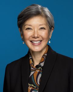 Portrait of Changent team member Charlotte Min-Harris smiling against a blue background.