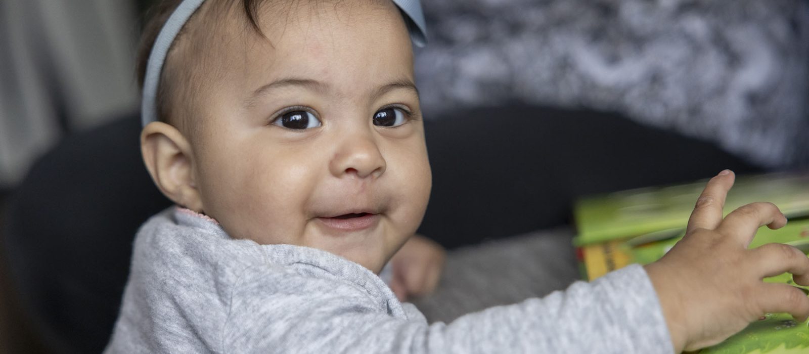 A baby with a medium skin tone is playing with a toy indoors.