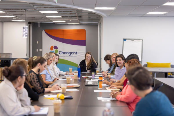 A group of Changent staff gathered around a boardroom table, actively engaging in conversation.